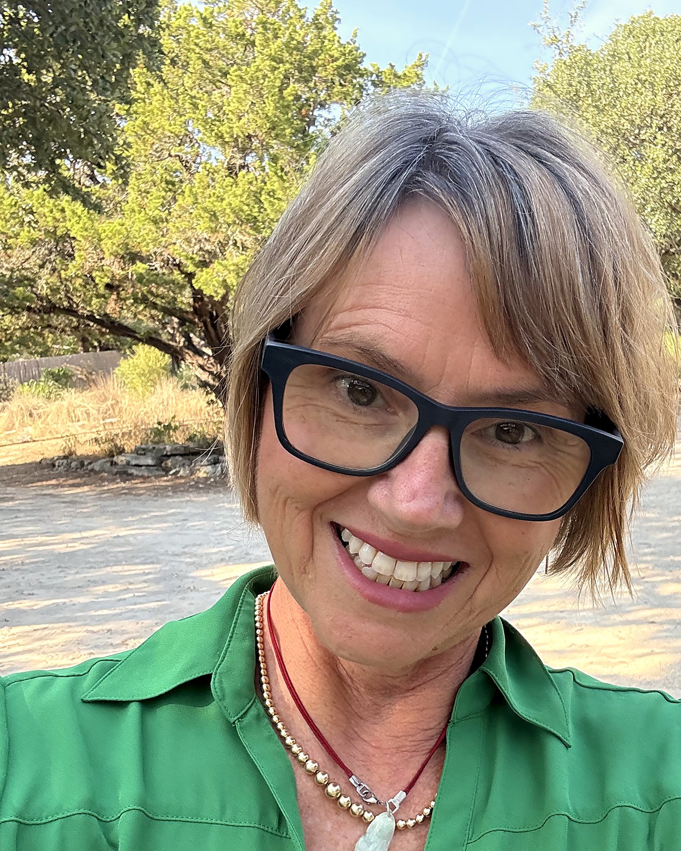 Kirsten Karchmer smiling outdoors in a green shirt